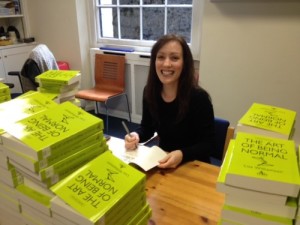 Lisa beaming over a stack of her debut novel.